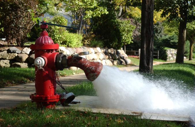 Water sprays out of a hydrant with a flushing elbow attached to it.
